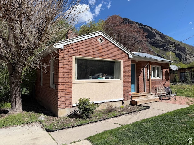 bungalow-style house with a mountain view, brick siding, and a chimney