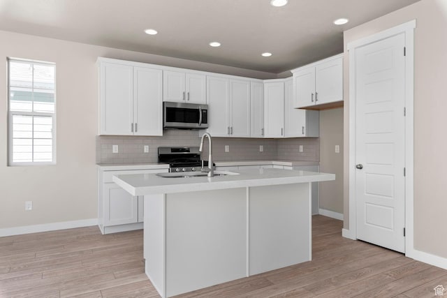 kitchen with appliances with stainless steel finishes, a sink, light countertops, baseboards, and recessed lighting