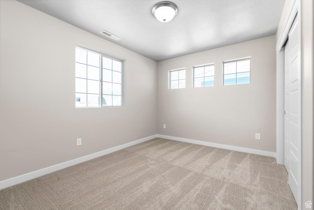 unfurnished bedroom with light colored carpet, baseboards, and a closet