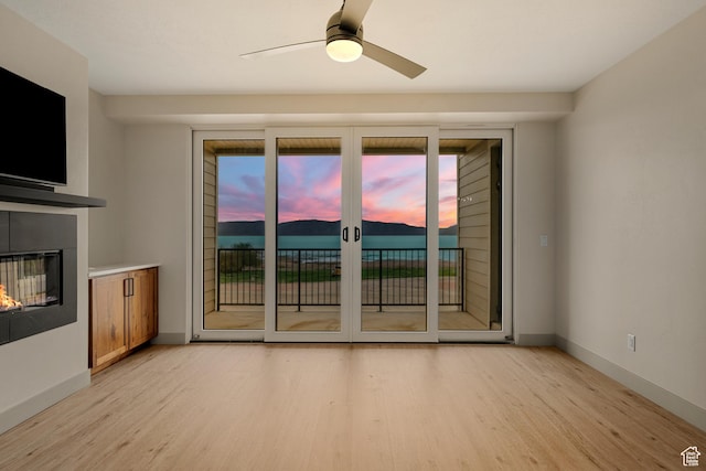 unfurnished living room featuring light wood-style floors, a glass covered fireplace, and baseboards
