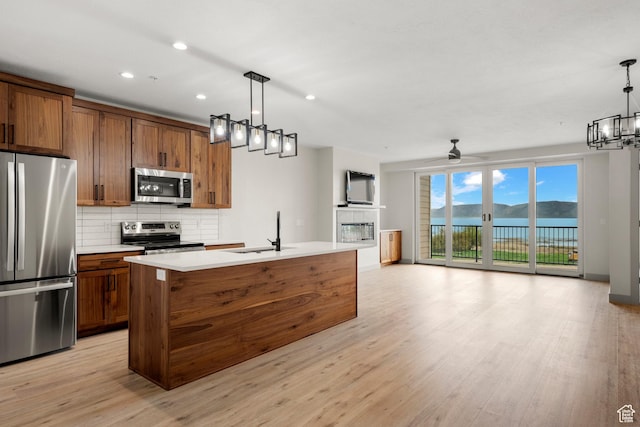 kitchen with appliances with stainless steel finishes, a sink, open floor plan, backsplash, and recessed lighting