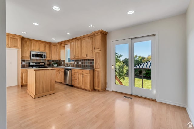 3236 W New World Dr S, West Jordan, UT 84084 - kitchen with appliances with stainless steel finishes, decorative backsplash, a center island, light wood-type flooring, and recessed lighting