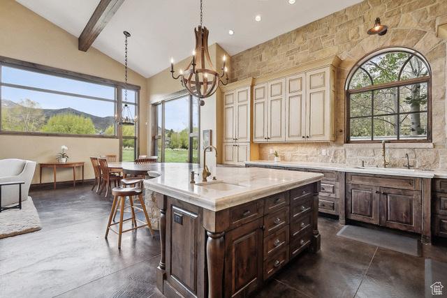 4891 Last Stand Dr, Snyderville, UT 84098 - kitchen featuring a sink, concrete floors, a breakfast bar, cream cabinetry, and a chandelier