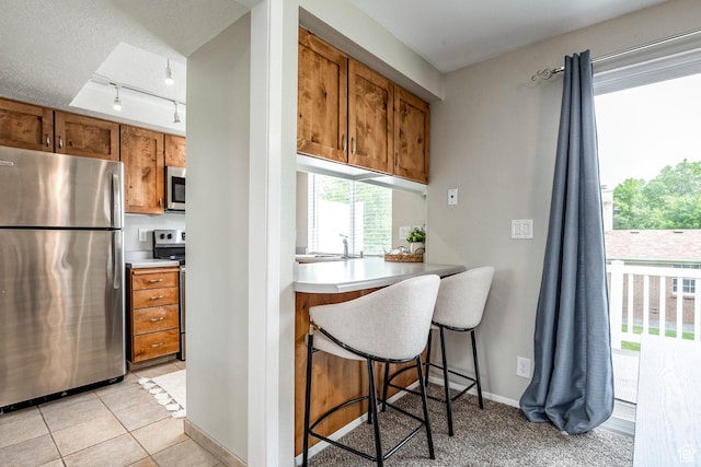 1180 W Middlesex Rd S, Taylorsville, UT 84123 - kitchen with stainless steel appliances, brown cabinets, track lighting, a kitchen bar, and light countertops