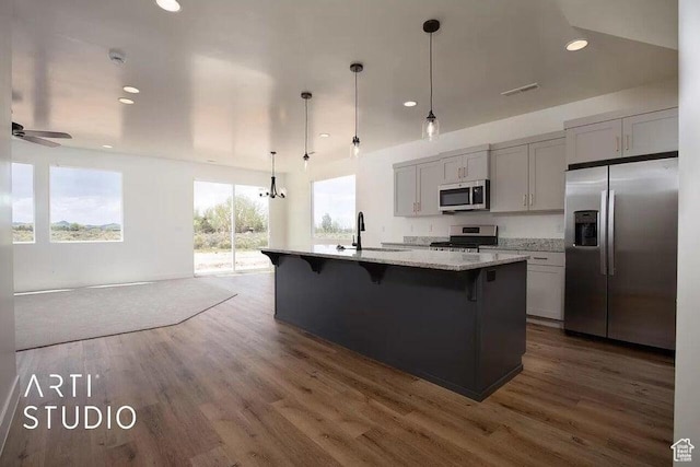 4883 N 10 E, Enoch, UT 84721 - kitchen featuring appliances with stainless steel finishes, dark wood-style flooring, a kitchen breakfast bar, an island with sink, and light stone countertops