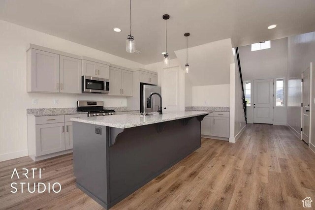 4883 N 10 E, Enoch, UT 84721 - kitchen with stainless steel appliances, light wood-type flooring, a kitchen breakfast bar, a sink, and an island with sink