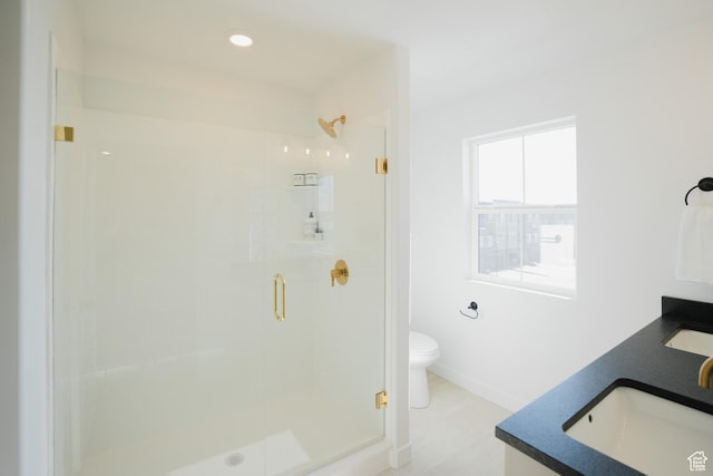 bathroom with a stall shower, toilet, baseboards, double vanity, and recessed lighting