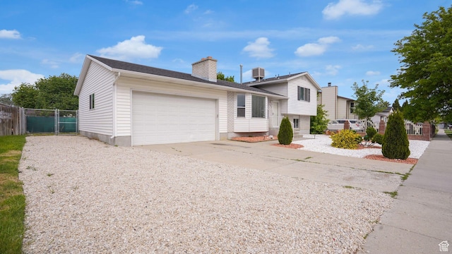 2976 S Laree St, West Valley City, UT 84120 - tri-level home featuring concrete driveway, a garage, a chimney, and cooling unit