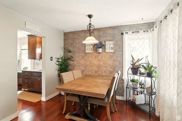 575 5th St, Ogden, UT 84404 - dining area featuring dark wood finished floors, an accent wall, baseboards, and a textured ceiling