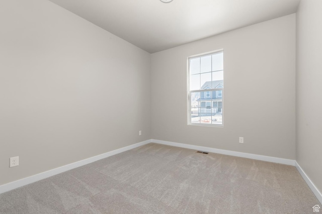 unfurnished room featuring light carpet and baseboards
