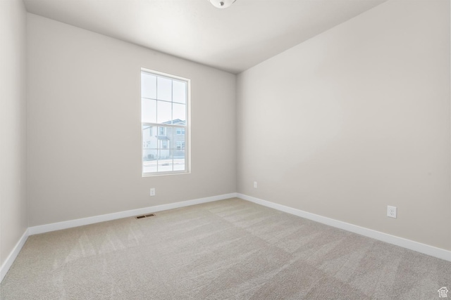 unfurnished room featuring light carpet and baseboards