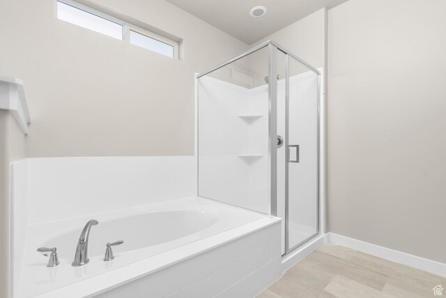 full bath featuring a stall shower, wood finished floors, and a garden tub