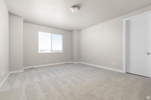 spare room with light colored carpet and baseboards