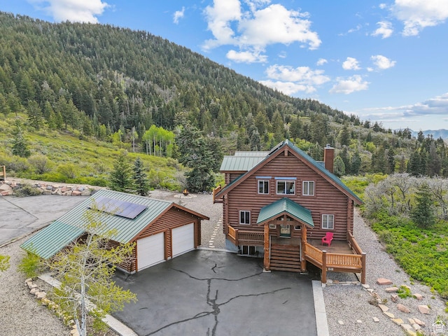 450 Crestview Dr, Summit Park, UT 84098 - view of front facade with a forest view, log exterior, a detached garage, a chimney, and an outbuilding