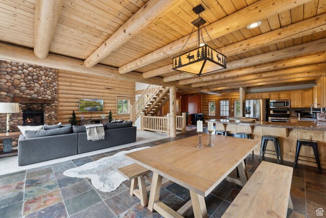 450 Crestview Dr, Summit Park, UT 84098 - dining room featuring wooden ceiling with exposed beams, a stone fireplace, log walls, stairs, and stone tile flooring