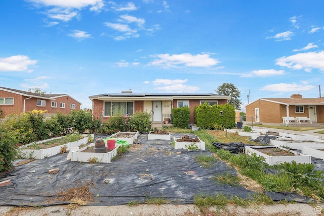 3466 W 4305 S, West Valley City, UT 84119 - view of front of home featuring a garden, brick siding, and roof mounted solar panels