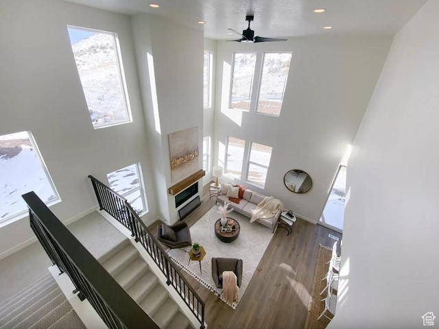 5894 N Canyon Rim Rd E Unit 621, Lehi, UT 84043 - living room featuring healthy amount of natural light, a towering ceiling, baseboards, a glass covered fireplace, and a ceiling fan