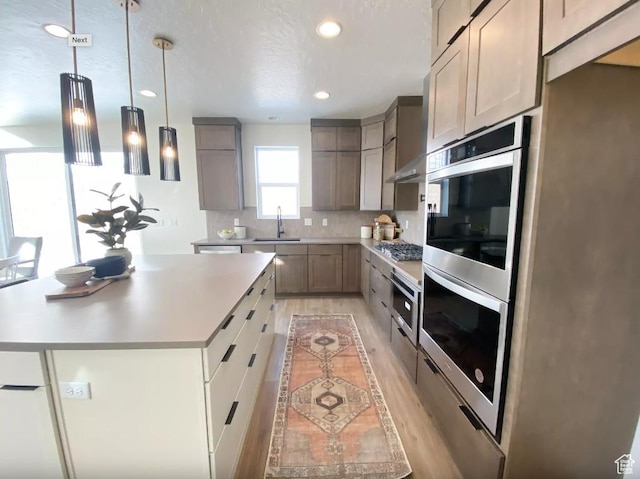5894 N Canyon Rim Rd E Unit 621, Lehi, UT 84043 - kitchen with a sink, light wood-type flooring, appliances with stainless steel finishes, light countertops, and decorative backsplash
