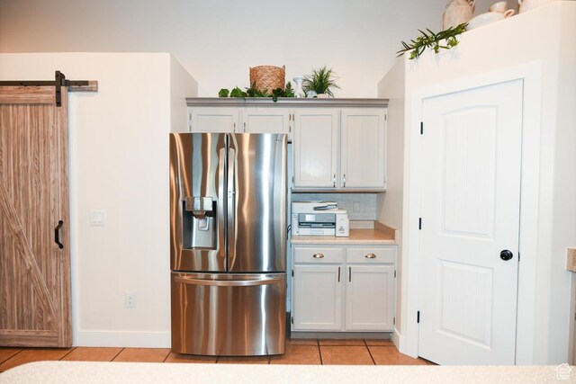 3155 S Autumn Blaze Cv W, West Valley City, UT 84128 - kitchen with stainless steel fridge with ice dispenser, light tile patterned floors, light countertops, baseboards, and a barn door