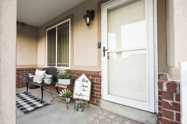 3155 S Autumn Blaze Cv W, West Valley City, UT 84128 - view of exterior entry featuring a porch, brick siding, and stucco siding