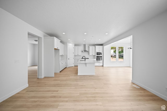 132 E Heron Ave S Unit 806, Saratoga Springs, UT 84045 - kitchen featuring wall chimney range hood, built in microwave, white cabinetry, a kitchen island with sink, and stainless steel oven