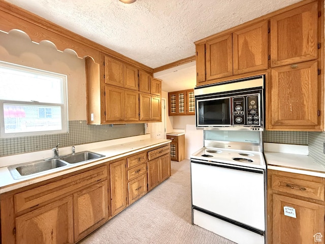 kitchen featuring white range with electric cooktop, a sink, light countertops, backsplash, and brown cabinets