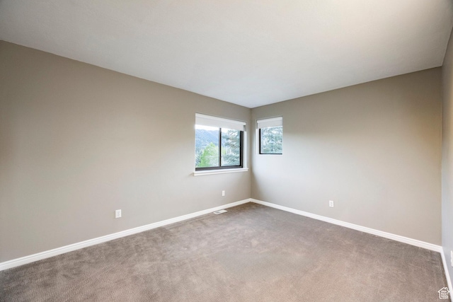 unfurnished room with baseboards and dark carpet