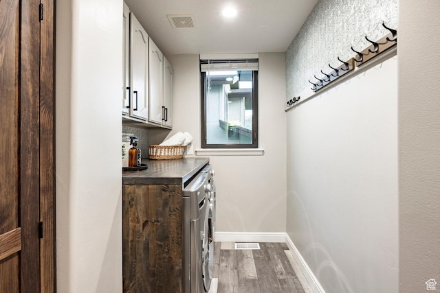 laundry room with cabinet space, washing machine and clothes dryer, dark wood finished floors, and baseboards