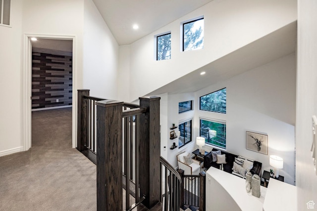 hallway featuring carpet, an upstairs landing, high vaulted ceiling, recessed lighting, and baseboards
