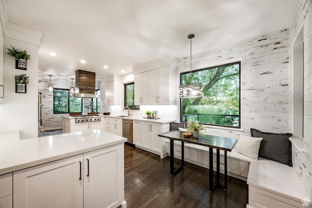 kitchen with appliances with stainless steel finishes, a sink, white cabinets, a peninsula, and pendant lighting