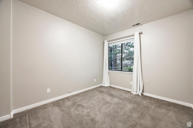 carpeted spare room featuring a textured ceiling and baseboards