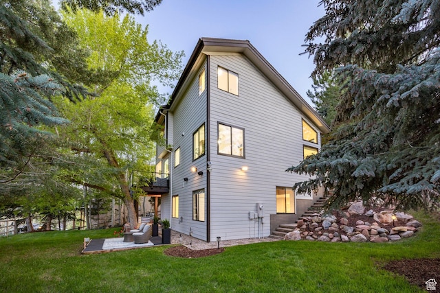 rear view of house with stairs, a patio area, a yard, and a balcony