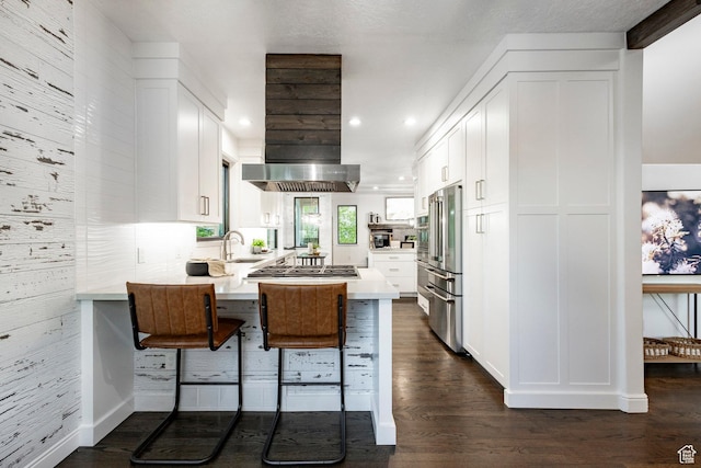 kitchen with stainless steel appliances, ventilation hood, a peninsula, white cabinets, and recessed lighting
