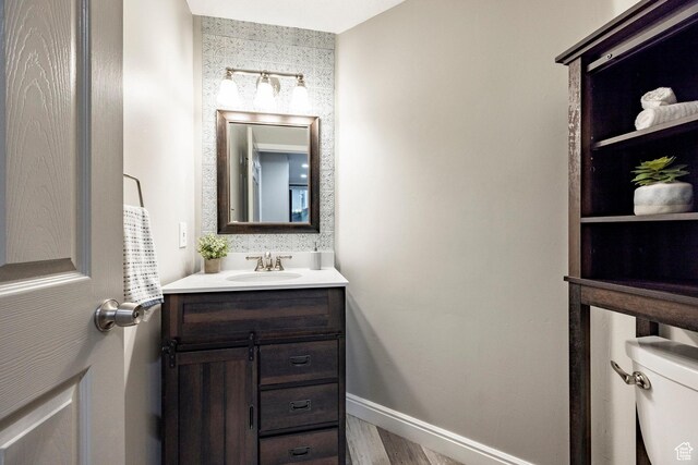 half bath featuring toilet, vanity, and baseboards
