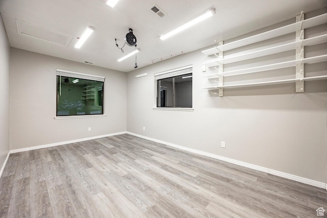 spare room with wood finished floors, attic access, and baseboards