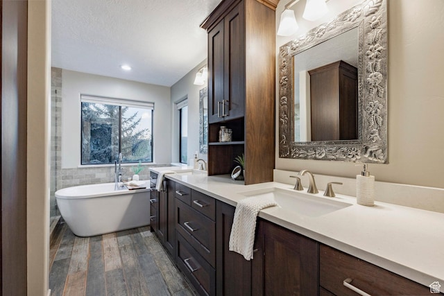full bathroom with wood finished floors, a freestanding bath, and double vanity
