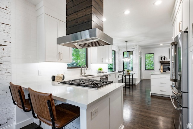 kitchen with high end fridge, a sink, a peninsula, baseboards, and white cabinetry