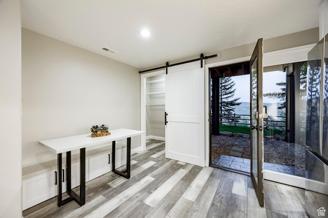 unfurnished dining area with a barn door, wood finished floors, and recessed lighting