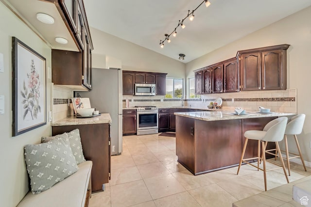 2057 W Marblewood Dr, Riverton, UT 84065 - kitchen with stainless steel appliances, a peninsula, vaulted ceiling, decorative backsplash, and dark brown cabinets