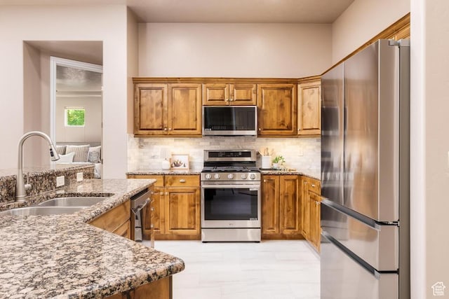 8 S Arroyo Dr, St George, UT 84790 - kitchen featuring stainless steel appliances, a sink, brown cabinetry, decorative backsplash, and stone countertops