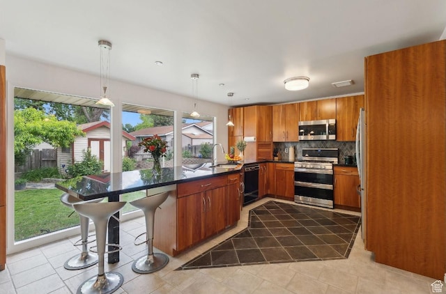 635 E Pioneer Ave S, Sandy, UT 84070 - kitchen with stainless steel appliances, a peninsula, backsplash, brown cabinets, and dark countertops