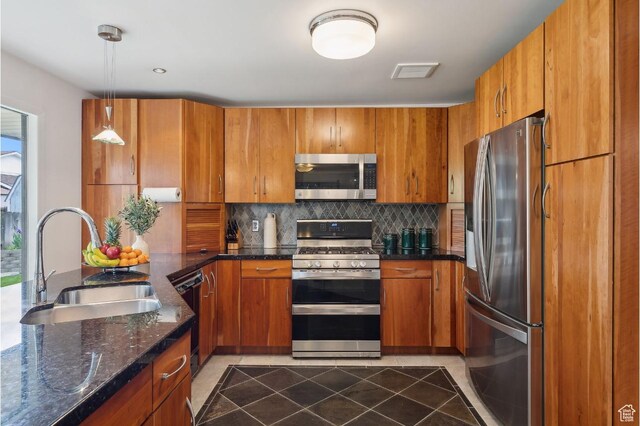 635 E Pioneer Ave S, Sandy, UT 84070 - kitchen featuring stainless steel appliances, a sink, brown cabinetry, backsplash, and dark tile patterned floors