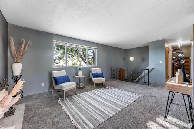 sitting room with an upstairs landing, carpet flooring, and a textured ceiling