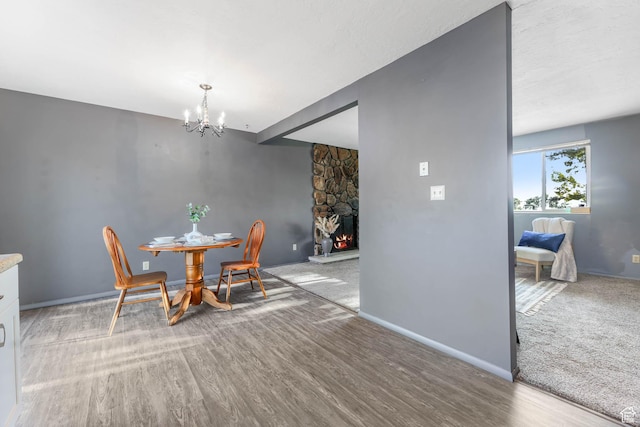 dining space with a chandelier, wood finished floors, a fireplace, and baseboards