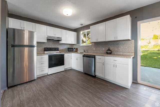 kitchen featuring appliances with stainless steel finishes, under cabinet range hood, white cabinets, tasteful backsplash, and dark wood finished floors
