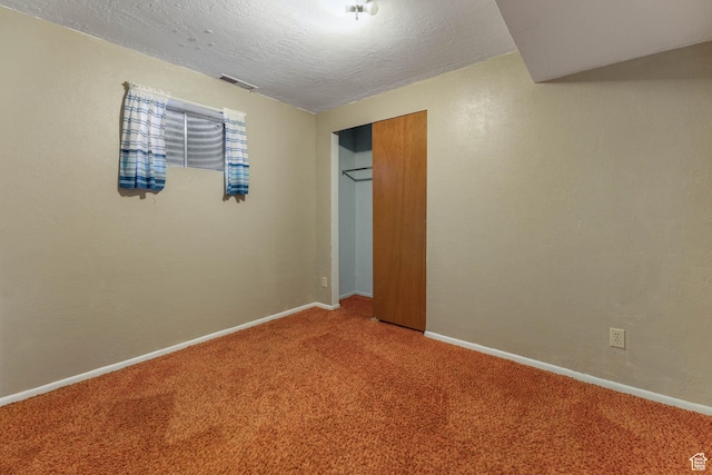 unfurnished bedroom featuring carpet, a closet, baseboards, and a textured ceiling