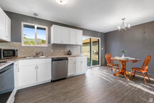 kitchen featuring stainless steel appliances, a sink, dark wood-type flooring, a chandelier, and decorative backsplash