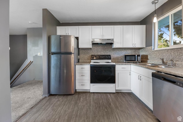 kitchen with appliances with stainless steel finishes, under cabinet range hood, a sink, dark wood-style floors, and decorative backsplash