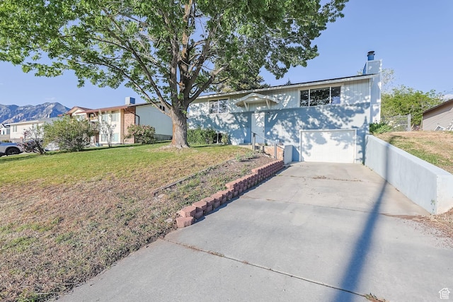 view of front of house featuring an attached garage, concrete driveway, and a front lawn