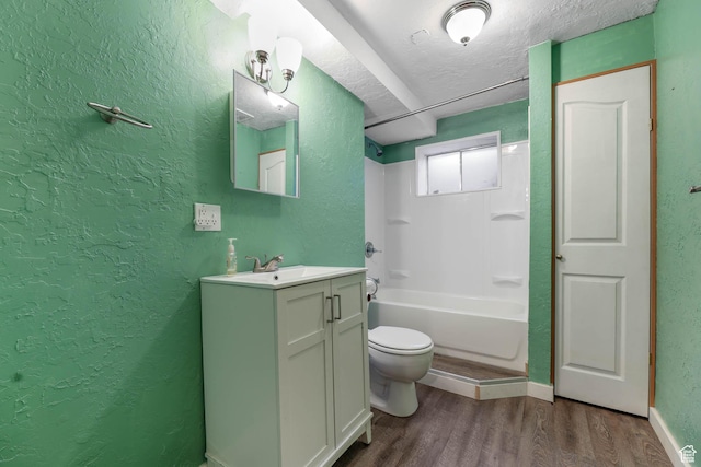 bathroom featuring a textured wall, wood finished floors, toilet, shower / washtub combination, and vanity